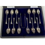A hallmarked silver set of 12 teaspoons and tongs with scroll terminals, cased, London 1887, 4 oz