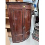 A Georgian inlaid mahogany corner cupboard with bow front enclosed by 2 doors