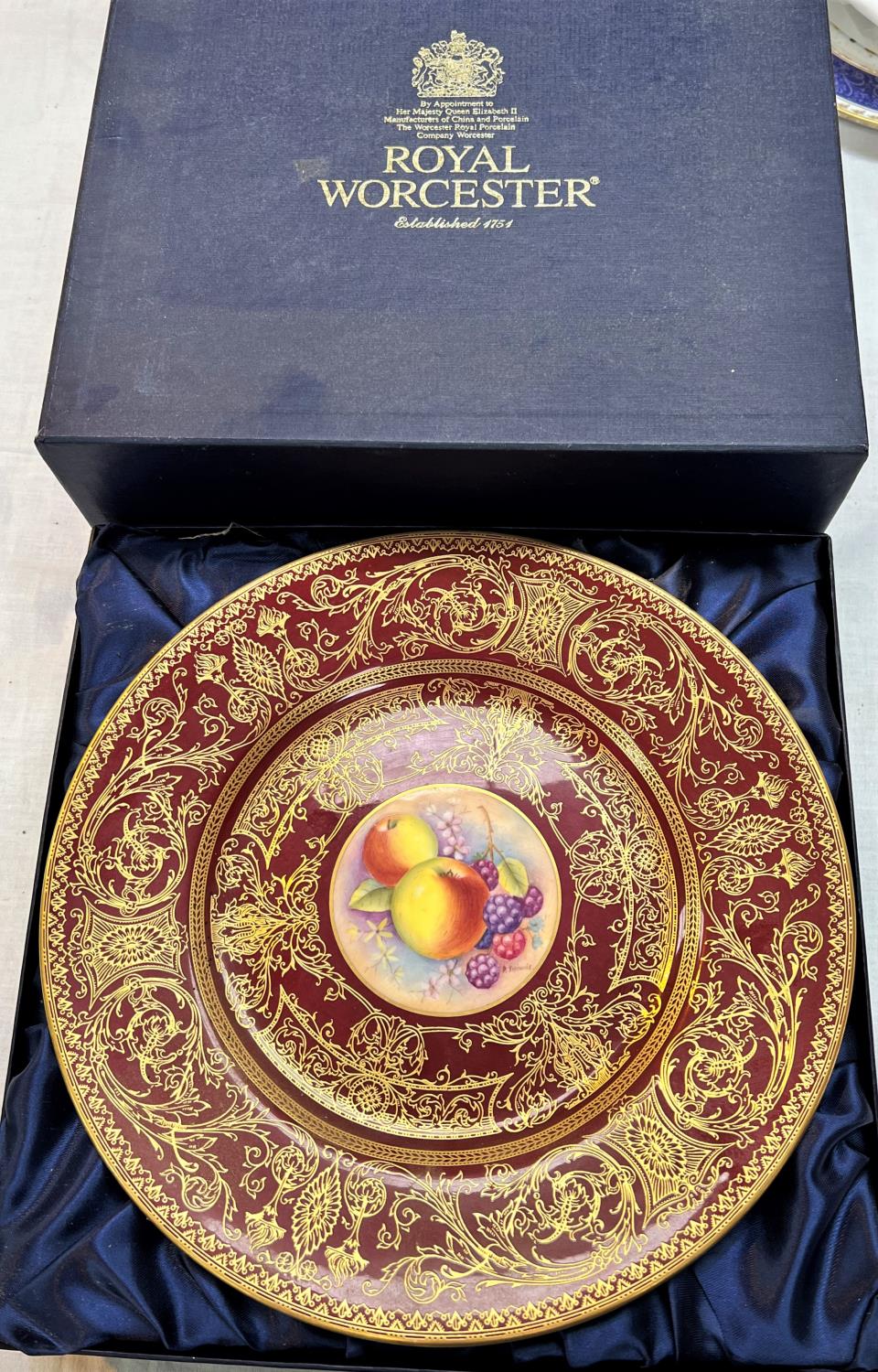 A Royal Worcester plate with hand painted central fruit panel, signed D Shinnie, red ground and