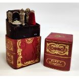 A red and gilt leather ladies companion set in book type case with white metal accessories in fitted