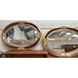 A pair of oval gilt framed wall mirrors.