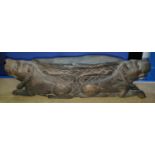 A carved wooden tribal style thin bowl atop double crouching lions