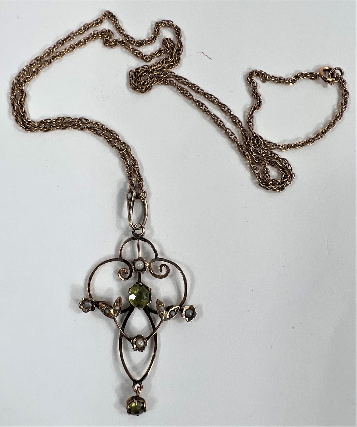 An Edwardian yellow metal pendant set with peridots and seed pearls on yellow metal chain tested