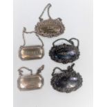 A hallmarked silver set of 3 ornate bottle labels:  Gin, Brandy & Whisky, London 1911-13; a pair