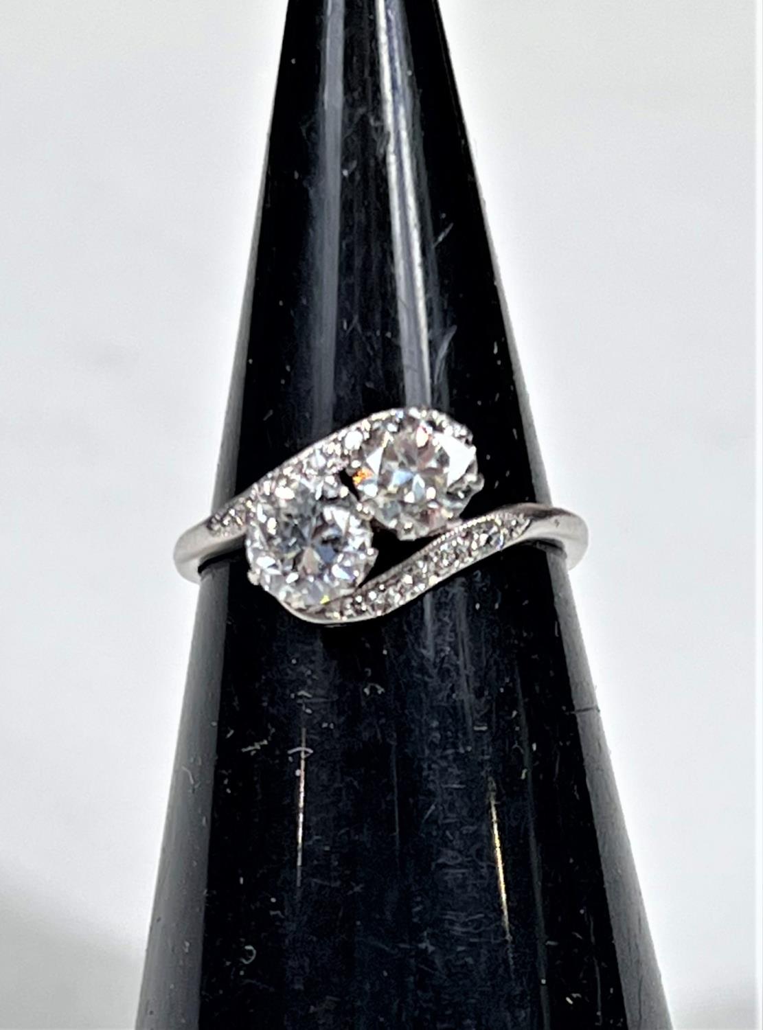 A white metal ring stamped 'Pt', with 2 diamonds in crossover setting, each shoulder set 4 small