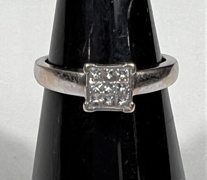 A white metal ring, stamped '750', with 9 square diamonds in square setting