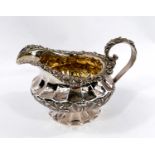 A late Georgian hallmarked silver cream jug of ribbed squat form with acanthus and shell border,