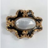 A Victorian yellow metal mourning brooch set with oval mother of pearl and with black enamel