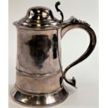 An 18th century silver tankard with domed hinge lid, shaped handle with heart shaped scrolling