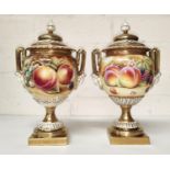 A pair of Royal Worcester two handled lidded urns, 'Hand Painted Study of Fruit', decorated with