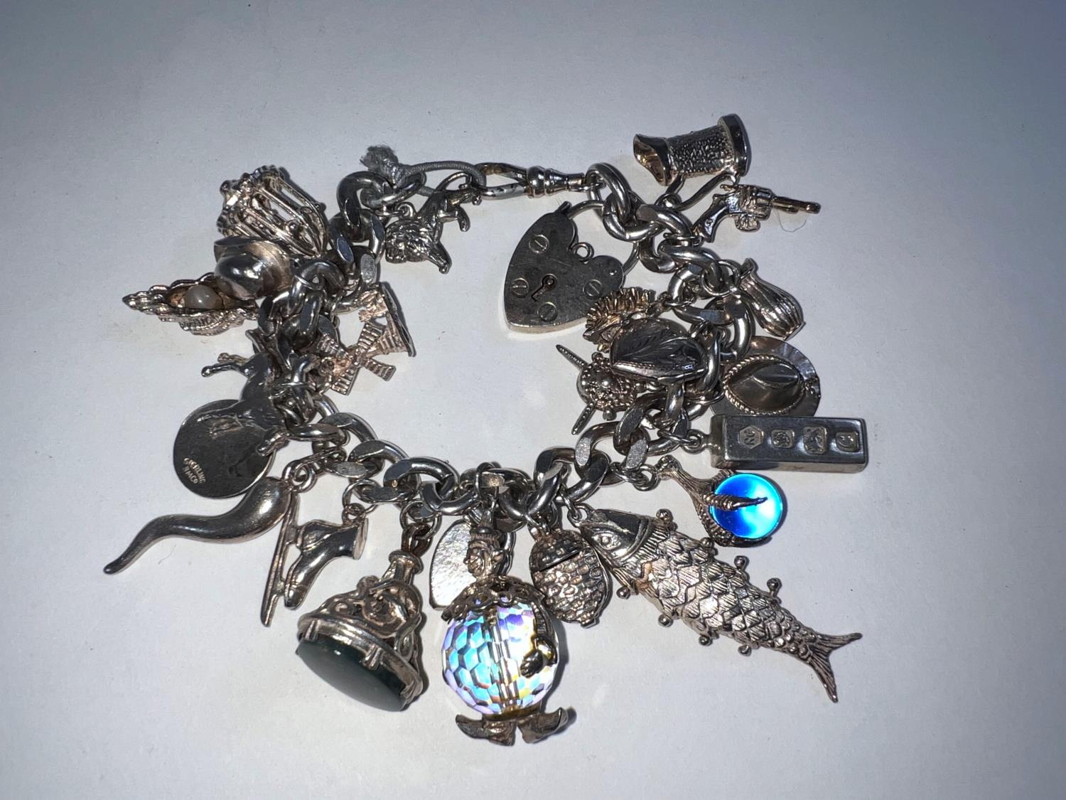 A silver coloured charm bracelet with hallmarked silver lock, some charms hallmarked (25 charms) 3.