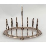 A hallmarked silver gothic arch toast rack with 6 divisions on chased oval base and 4 beaded pad