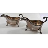 A hallmarked silver pair of sauce boats with 3 hoof feet, gadrooned rims and scrolled handles,