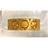 A wedding ring decorated with circular motifs, unmarked, tests as 18ct+, 4gm