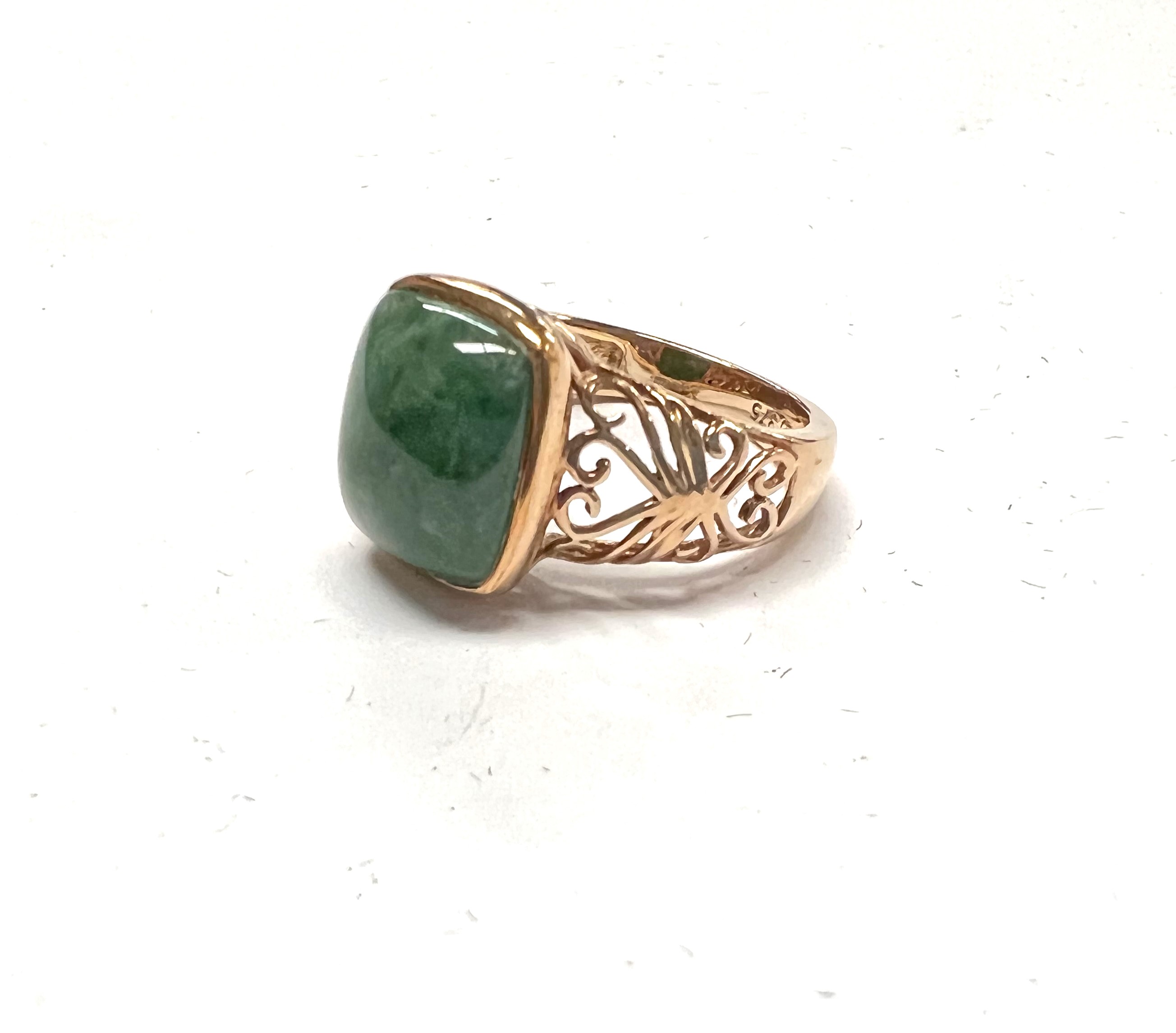 A 9 carat hallmarked gold dress ring set with a square domed jade coloured stone with pierced scroll
