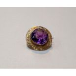 A yellow metal brooch with large central faceted amethyst coloured stone in shield shaped mount with