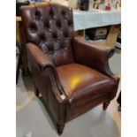 A brown leather button back armchair with gilded  decoration