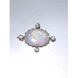 A large oval opal brooch with yellow metal settings and 4 diamonds to each quarter. 3.4gms.