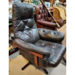 A mid 20th century Eames style swivel armchair in buttoned dark brown hide