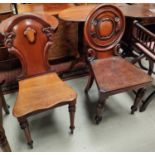 An early 19th century mahogany hall chair with rounded back and a similar shield back hall chair