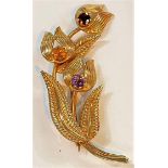 A 9 carat hallmarked gold brooch in the form of flowers and leaves, set coloured stones, 8.8gm