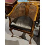 An early 20th century walnut bergère armchair, tub shaped with shell carved decoration, on
