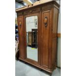 A French Provincial style oak wardrobe with triple doors, central mirror and carved decoration,