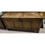 An 18th century oak blanket box with hinged lid, carved decoration, four front panels and block