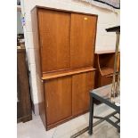 A teak full height side cabinet enclosed by 2 pairs of sliding doors