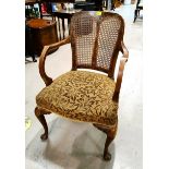 An early 20th century walnut armchair with bergère back and overstuffed seat, on cabriole legs