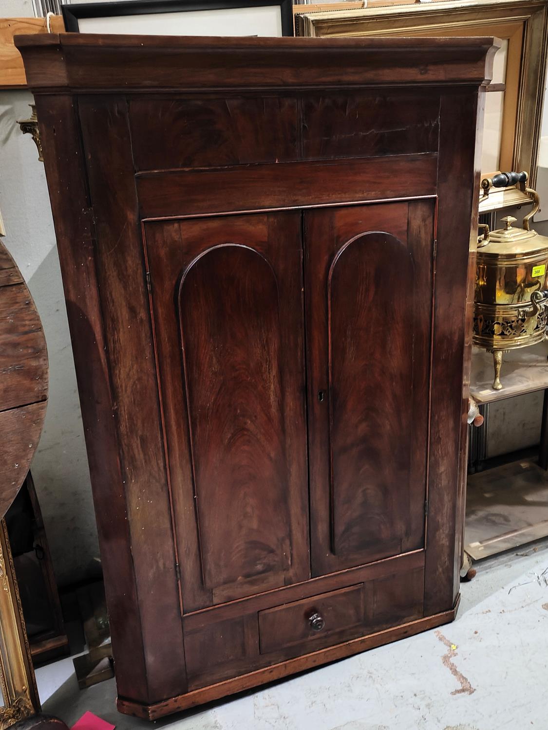 A Georgian mahogany corner cupboard with double arch doors and small drawer below