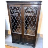 An Ercol modern display cabinet/bookcase with double leaded glass doors over linen fold panel doors