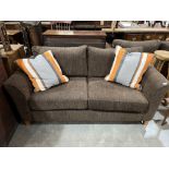 A two seater sofa upholstered in brown cord fabric with a pair of striped scatter cushions. 68'