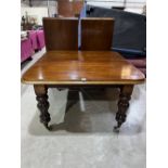 A Victorian mahogany dining table raised on lobed bulbous legs with brass caps and castors.