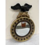 A Regency circular gilt looking glass, the ball applied frame with reeded slip and eagle carved