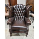 A leather armchair with deep-buttoned wing back on cabriole legs