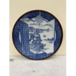 An Arita charger painted in blue and white with a landscape. 12½' diam.