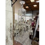 A French twelve light cut glass chandelier, the scrolled arms in two tiers, hung with swag and