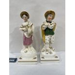 A pair of 19th century Staffordshire figures, rustic boy and female companion, each brightly painted