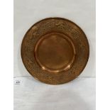 An Arts and Crafts copper dish, repousse decorated with trailed vine fruits. 11¼' diam.