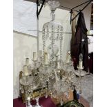 A French twelve light cut glass chandelier, the scrolled arms in two tiers, hung with swag and