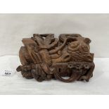 An oriental hardwood box, carved with serpents in high relief. 8' wide. Losses