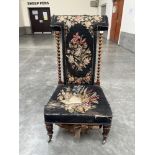 A Victorian rosewood prie-dieu chair with distressed tapestry back and seat raised on lappet moulded