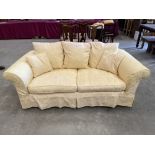 A 6' sofa, loose covered in gold floral damask, with a pair of scatter cushions