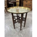 A Benares brass tray-top table on spindle turned folding base. 23' diam