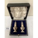 A pair of cased George V silver pepperettes. Birmingham 1915. 2¾' high. 17dwts