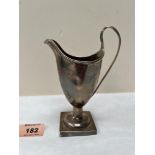 A George III silver helmet cream jug with reeded handle and rim, raised on a loaded square foot.