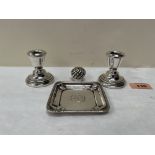 A pair of silver squat candlesticks; a silver pin dish and a silver bottle cap