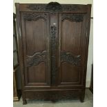 A 19th century French joined oak armoire, carved with trailing foliage, enclosed by a pair of