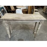 A distressed pine side table on turned legs. 48' wide